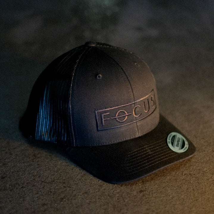 Black cap with 'FOCUS' logo on a textured surface